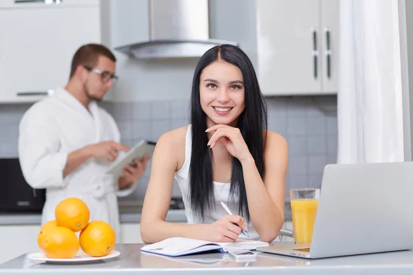 Couple using gadgets and studying at kitchen. — Stock Photo, Image