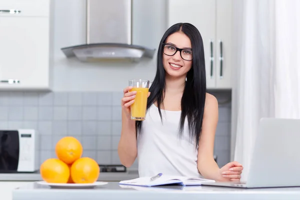 Chica en gafas de escribir tarea en casa en la cocina . — Foto de Stock