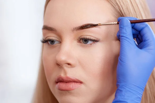Cosmetologist que faz sobrancelhas permanentes usando a escova . — Fotografia de Stock