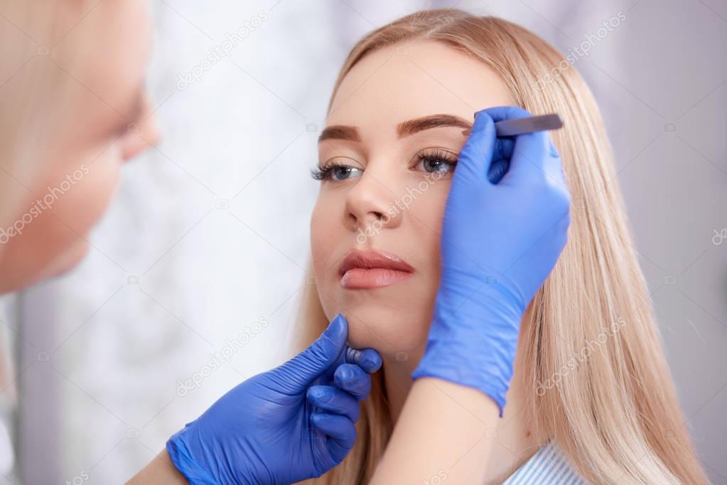 Professional using forceps for plucking eyebrows.