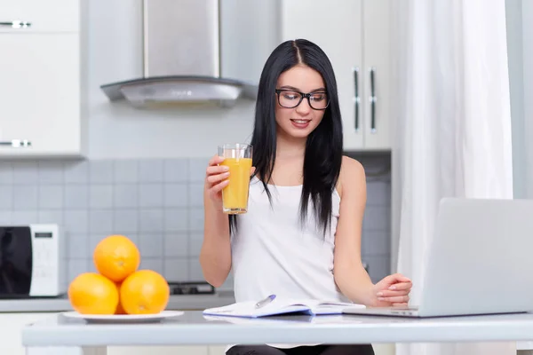 Ragazza in occhiali scrivere compito a casa in cucina . — Foto Stock