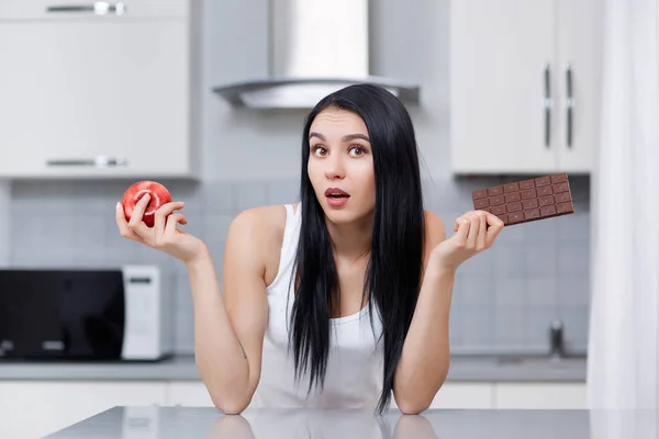 Жінка на дієті вибирає яблуко або шоколад здивований вигляд . — стокове фото