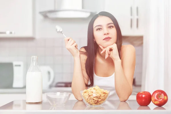 Junge Frau in weißen Kleidern sitzt in der Küche — Stockfoto