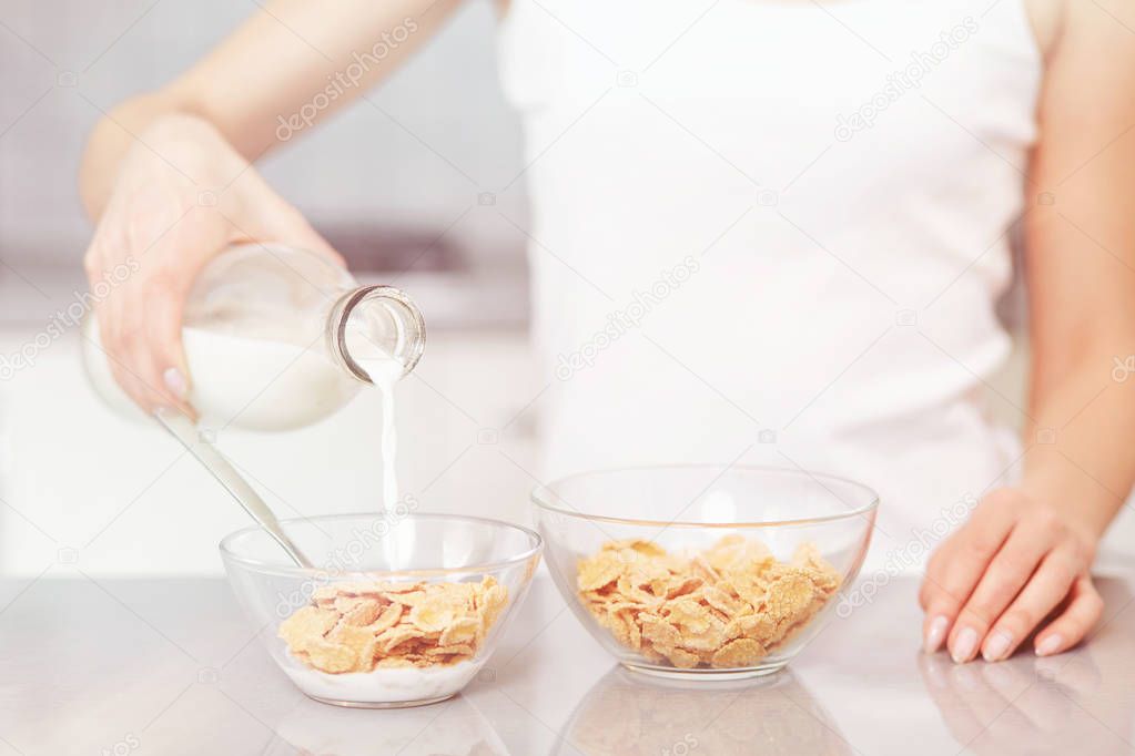 Female pouring milk in plate with oak flakes.