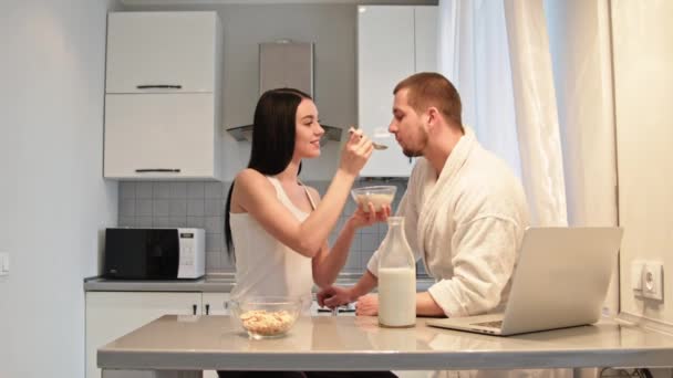 Hermosa esposa alimentando a su marido de copos de avena con leche . — Vídeos de Stock