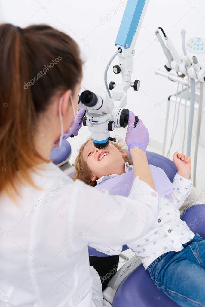 Woman examining girl with microscope