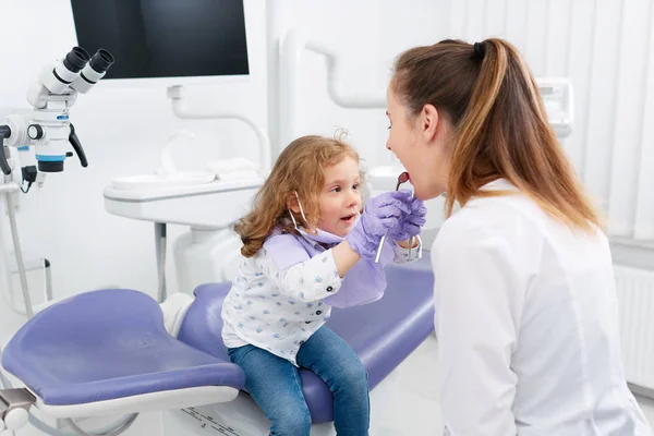 Kleines Mädchen schaut in den Mund des Zahnarztes — Stockfoto