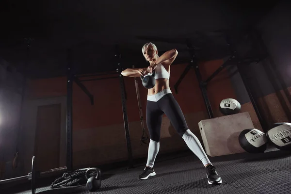 Gespierde jonge fitness vrouw tillen een gewicht in de sportschool — Stockfoto