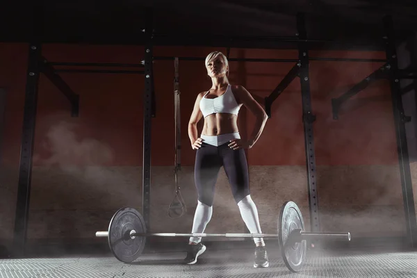 Muskulöse junge Fitness-Frau, die im Fitnessstudio ein Gewicht hebt — Stockfoto