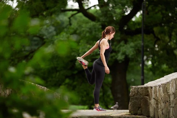 Sportvrouw die zich uitstrekt in zomer park — Stockfoto