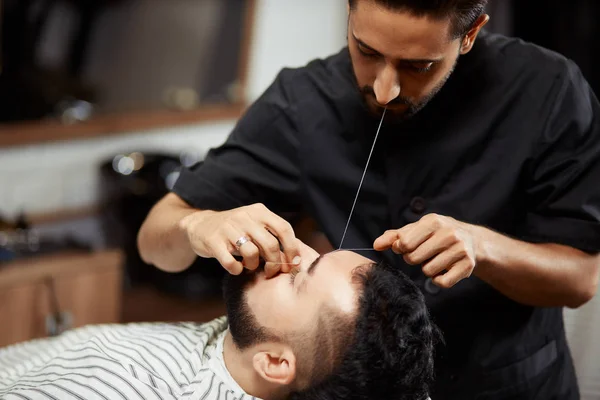 Barber grooming ung man i stol — Stockfoto