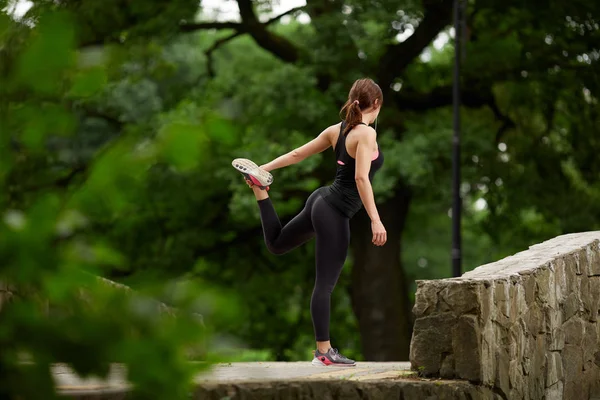Sportswoman stretching in summer park — Stock Photo, Image