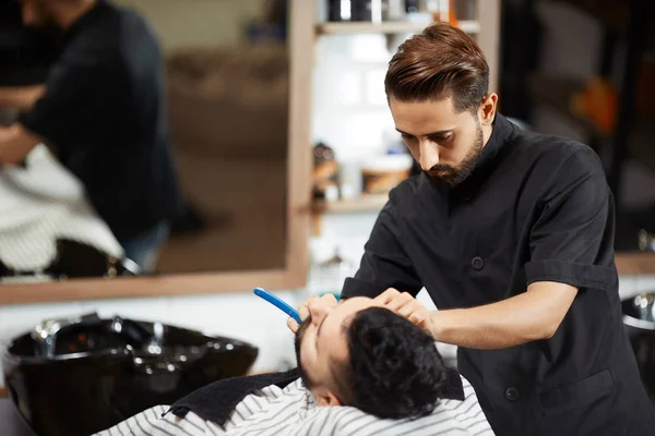 Friseur in schwarzer Suite rasiert und schneidet Brot des Kunden. — Stockfoto