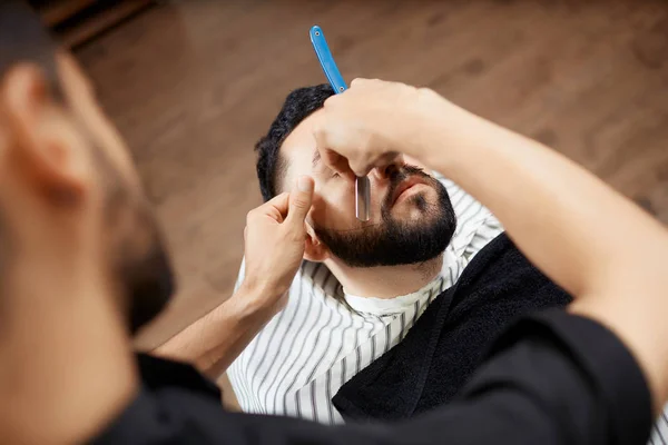 Peluquería en peluquería cortando barba con afeitadora . — Foto de Stock