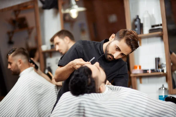 Dois estilistas cortando pão, fazendo corte de cabelo para os clientes na barbearia . — Fotografia de Stock