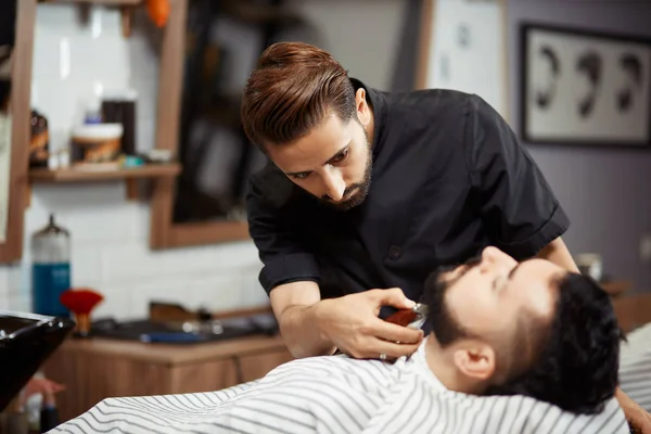 Peluquero negro trabajando en peluquería cortando pan para hombre . — Foto de Stock