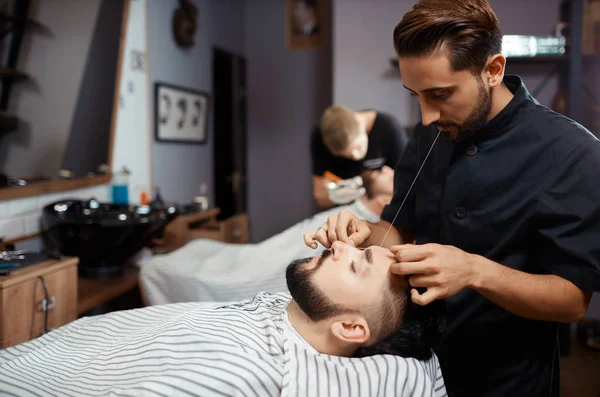 Brunet homem visitando barbearia para cortar barba de linha . — Fotografia de Stock