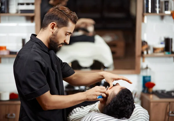 Professioneller Friseur in schwarzer Pflege und Brotschneiden für den Mann. — Stockfoto