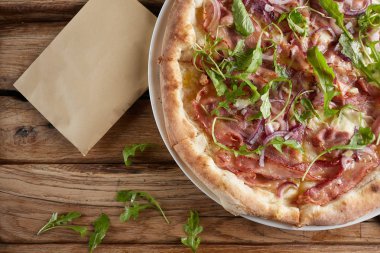 Süpürge, pastırma, peynir, salamura, kırmızı soğan ile İtalyan pizza.