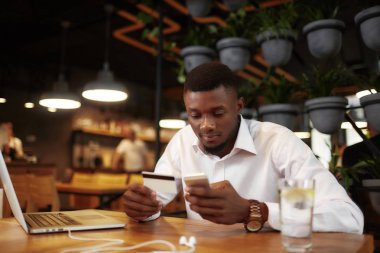 Afrika adam ödeme kartı aramak için telefon kullanarak Cafe.
