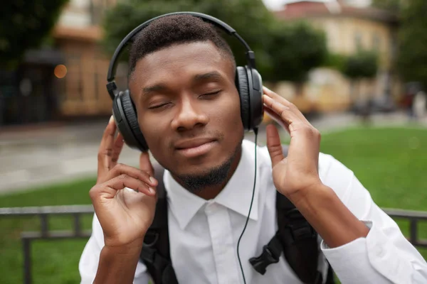 African man listening music in headphones with closed eyes and dreaming.