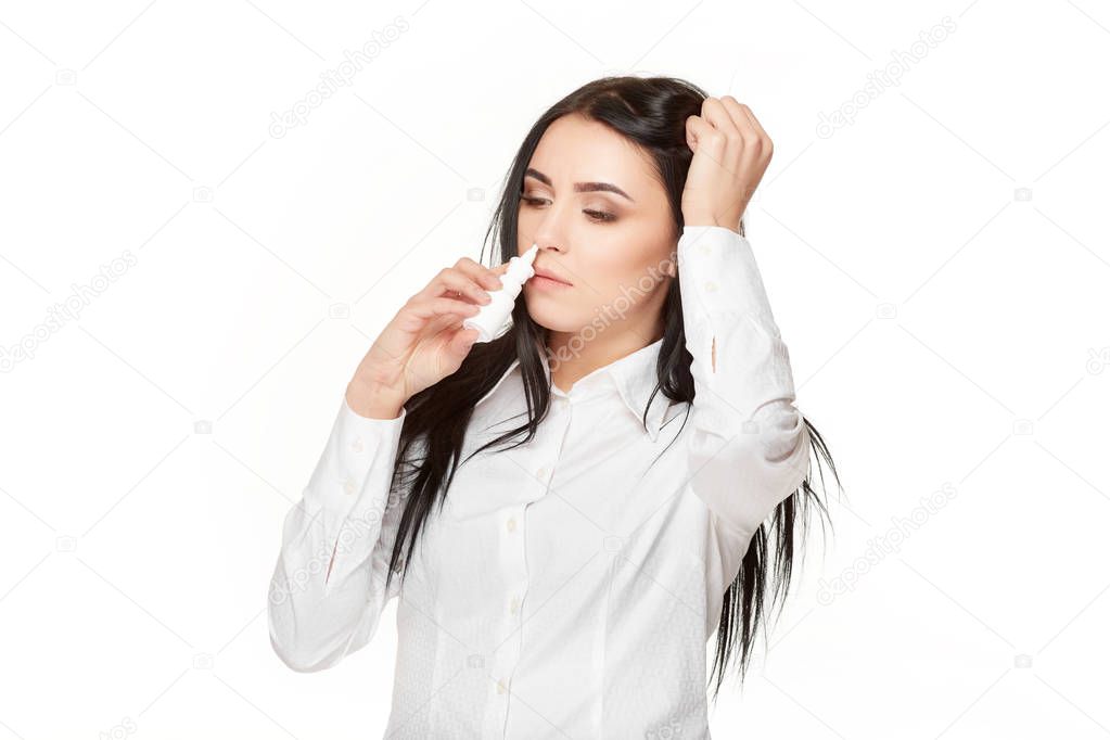Unhealthy brunette holding head by hand and drown spray in nose.
