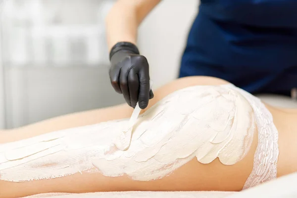 Cosmetologist anointing white clay mask on woman body. — Stock Photo, Image