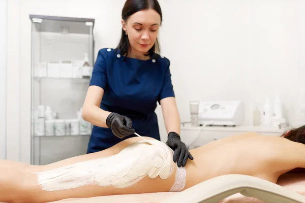 Atractiva mujer con máscara blanca en su cuerpo en el salón de belleza . —  Fotos de Stock