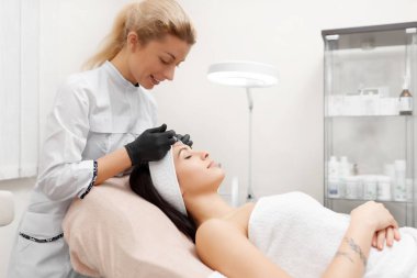 Enjeksiyon güzellik salonunda veren güzellik uzmanı yan görünüm.