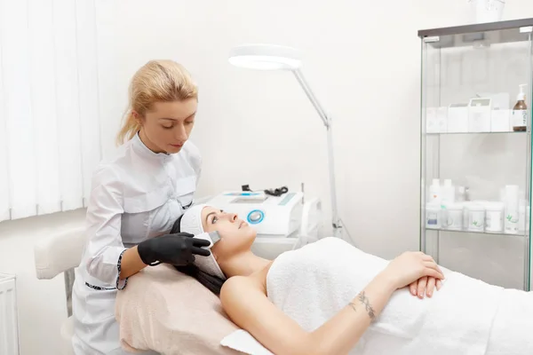 Attractive woman getting facial in modern beauty salon. — Stock Photo, Image