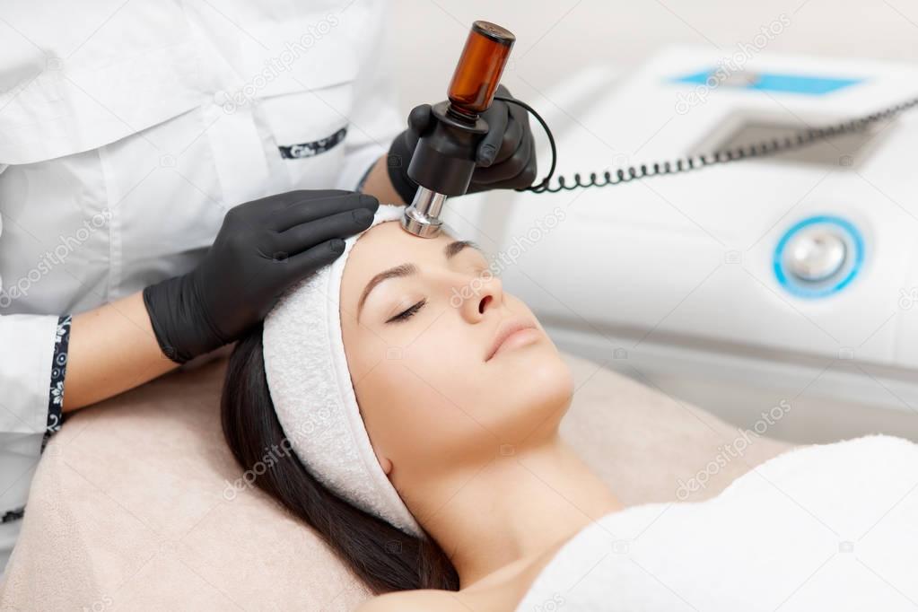 Cosmetology specialist doing radio frequency lifting in beauty salon.