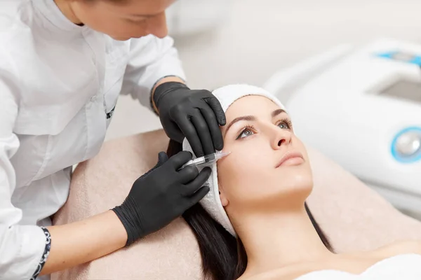 Beautician making anti-wrinkle injection in womans face. — Stock Photo, Image