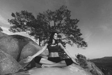 Dışarıda yoga yapan genç bir kadın.