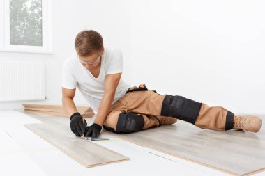 Marangoz, odaya kaplama döşeme kuruyor.