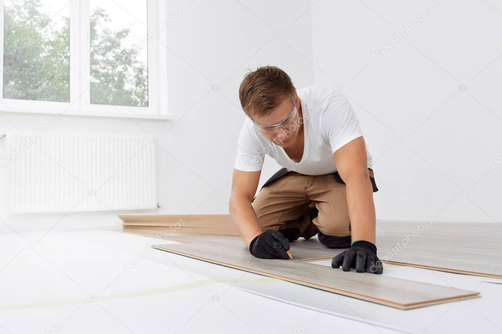 Craftsman installing laminate flooring in new apartment