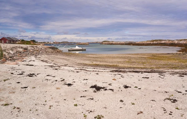 Shallow water in the bay, sandy beach, a pier on the fjord, moored boat — Stock Photo, Image