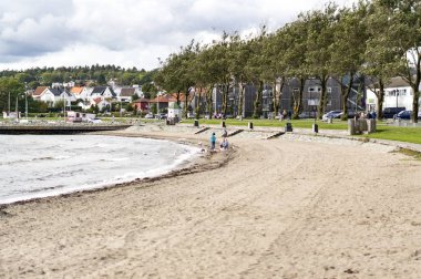 Moss Rygge, Norveç - 17 Eylül 2017: Moss kasabası, endüstriyel mirasa sahip çevre bölgeler, gelişen bir sanat sahnesi ve plajlar. Kumlu bir plaj. Körfezde gemiler ve feribotlar. Rüzgarlı gün. Geleneksel ahşap binalar. Küçük kırmızı ahşap 