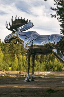 Osterdalen, Norveç - 17 Eylül 2017: Ormanda, gökyüzüne karşı bir Norveç geyiği heykeli. Gümüş dev geyik. 10 metre yüksekliğinde ve 12 metre uzunluğunda. Yazar Linda Bakke olduğunu.