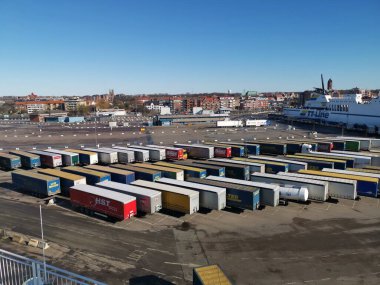 Trelleborg, İsveç - 14 Mart 2020: İsveç liman rıhtımının manzarası. Nakliye yarı römorkları feribota yüklenmeyi bekliyor. Renkli kamyonlar, yüksek liman binaları. Paskalyadan Önce Hareket