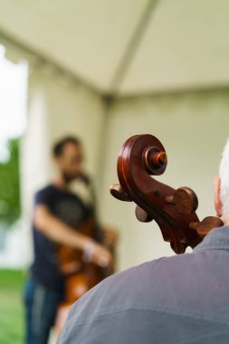 çadır altında oturan ve Çello çalan adam