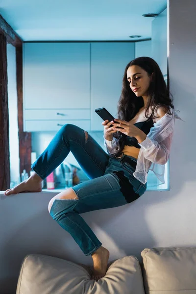 Modelo jovem sensual usando telefone em casa — Fotografia de Stock