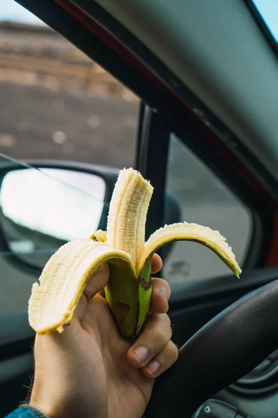 Pessoa comendo banana no carro — Fotografia de Stock