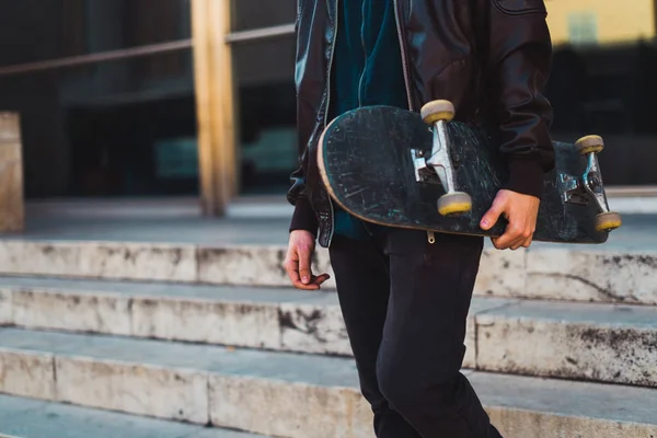 Crop man walking with skateboard in hands