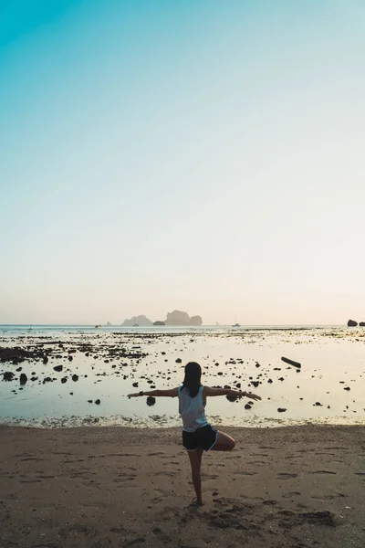 Mujer deportiva equilibrándose en la playa practicando yoga — Foto de Stock