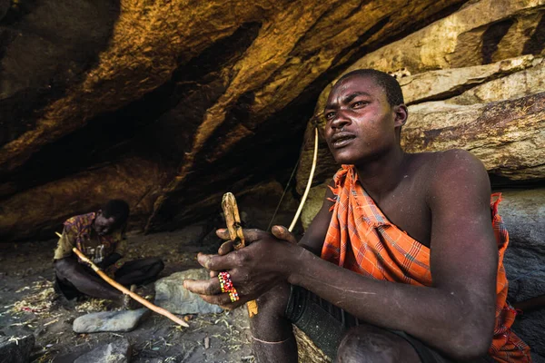 Eyasi lake, Tanzania, november, 23, 2019: African hunter sitting on rocks — Stock Photo, Image