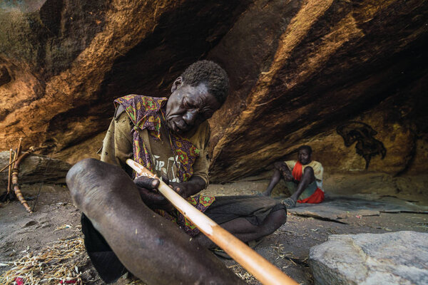 Eyasi lake, Tanzania, november, 23, 2019: African hunter grinding a wooden stick Royalty Free Stock Images