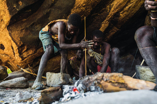 Eyasi lake, Tanzania, november, 23, 2019: two African hunters preparing fire Royalty Free Stock Images