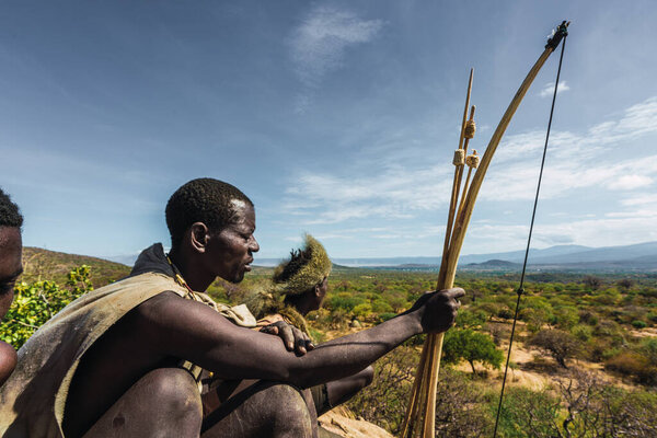 Eyasi lake, Tanzania, november, 23, 2019: hunters sitting on the savannah with bows Royalty Free Stock Photos