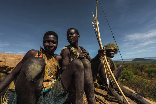 Eyasi lake, Tanzania, november, 23, 2019: three African hunters sitting on the savannah Royalty Free Stock Photos