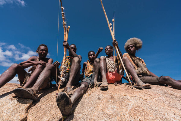 Eyasi lake, Tanzania, november, 23, 2019: African hunters sitting on a rock Stock Picture